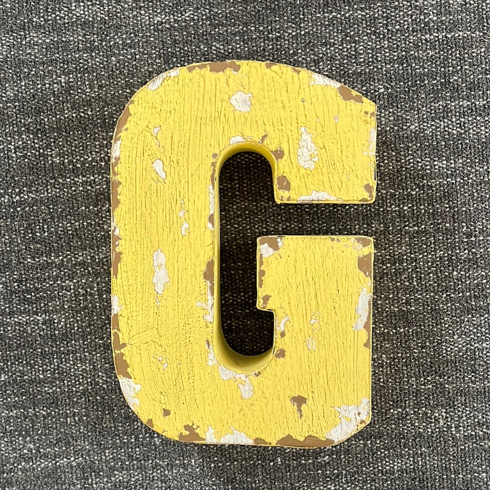 Decorative “G”. Yellow, distressed, has slots on back to hang on wall